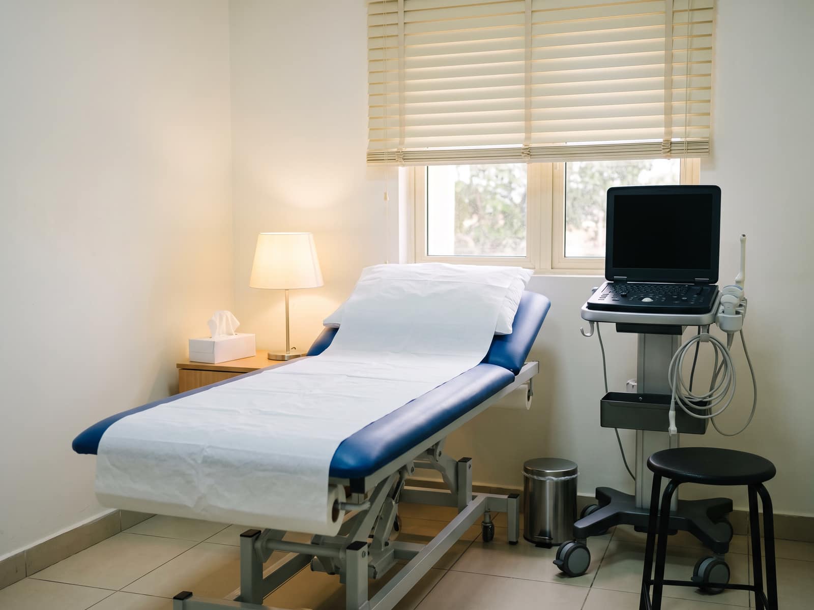 An ultrasound room with a couch, a scanning machine and a dimmed lamp